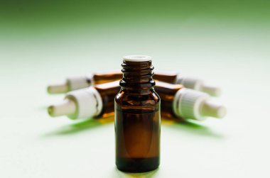 Kozmetoloji, cilt bakımı, içinde pipetler olan cam şişeler ve yeşil arka planda hyaluronik asit.