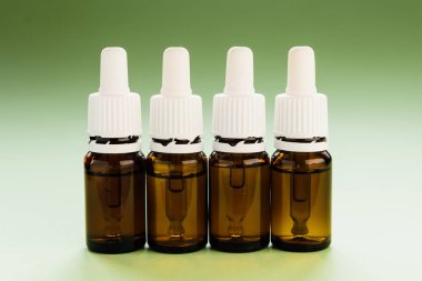 Kozmetoloji, cilt bakımı, içinde pipetler ve yeşil arka planda hyaluronik asit olan bir dizi cam şişe.