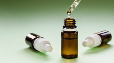 Kozmetoloji, cilt bakımı, içinde pipetler ve yeşil arka planda hyaluronik asit olan bir dizi cam şişe.