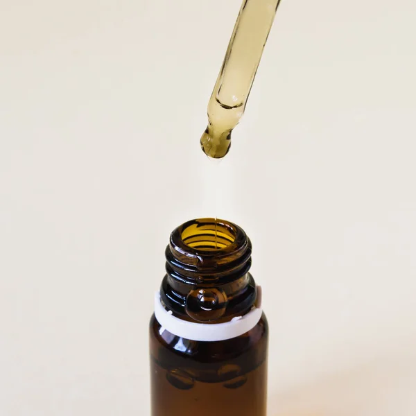 Primer plano, cosméticos, botella de vidrio con una pipeta y ácido hialurónico sobre un fondo amarillo —  Fotos de Stock