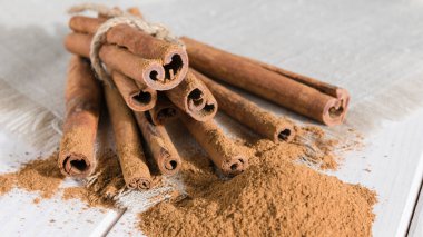 Yakın plan, beyaz ahşap bir masa üzerinde bütün çubuklarla tarçın.