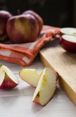 Durgun bir hayat, kırmızı elma dilimleri, beyaz bir masada tahta bir tahta üzerinde