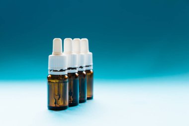 Kozmetik, pipetli cam şişeler ve mavi arka planda kozmetik.