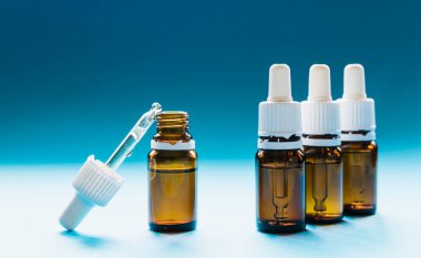 Kozmetik, pipetli cam şişeler ve mavi arka planda kozmetik.