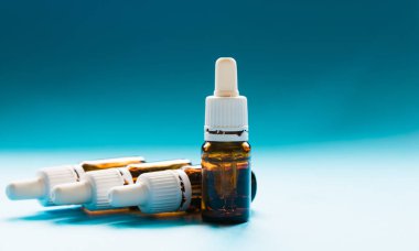 Kozmetik, pipetli cam şişeler ve mavi arka planda kozmetik.