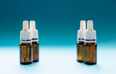 Kozmetik, pipetli cam şişeler ve mavi arka planda kozmetik.