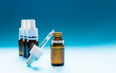 Kozmetik, pipetli cam şişeler ve mavi arka planda kozmetik.
