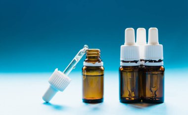 Kozmetik, pipetli cam şişeler ve mavi arka planda kozmetik.