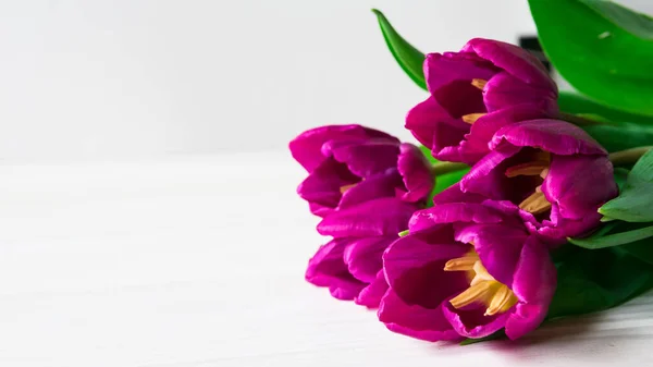 Ramo de tulipanes morados sobre una mesa de madera blanca — Foto de Stock