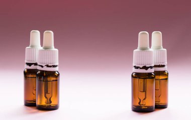 Kozmetik, pipetli cam şişeler ve pembe arka planda kozmetik.