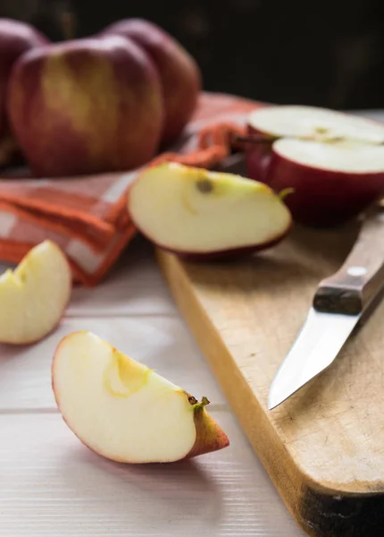 Still life, slices of red chopped apple, on a wooden board on a white table Stock Photo