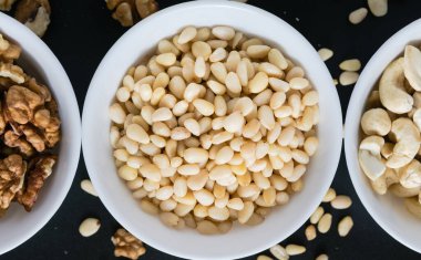 Süper yiyecek konsepti, sedir, ceviz, fındık, siyah arka planda bir tabakta.