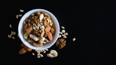 Badem, sedir, ceviz, fındık, siyah arka planda bir tabakta fındık.