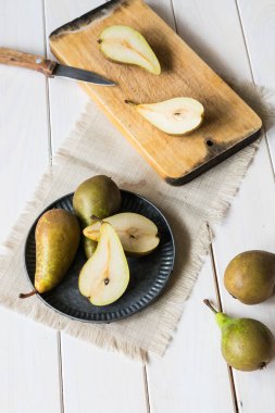 durgun bir hayat, yeşil armutlar beyaz tahta bir masada metal bir plaka, üst manzara