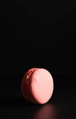 Tatlı reklamcılığı konsepti, Fransız tatlısı. Siyah arka planda pembe badem kurabiyesi. Yakın plan.