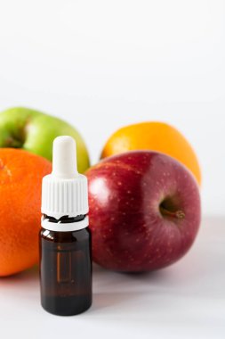 Meyve arka planında alfa hidroksi asitli serumla dolu cam şişe.