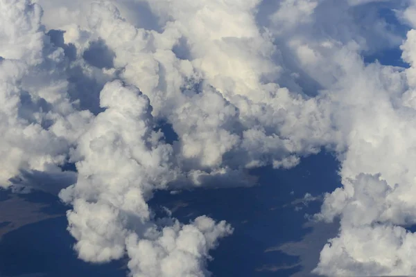 clusters of white clouds visible from above in the sky