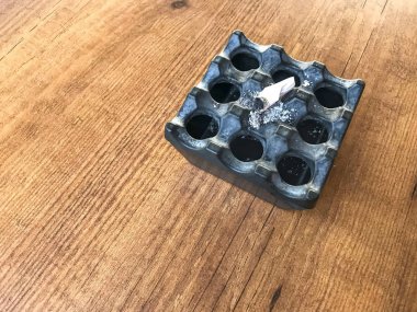 Siyah kül tablası ve siyah masada söndürülmüş sigara.