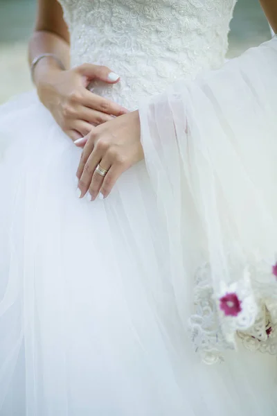 Bride dressed in wedding dress and her white hands