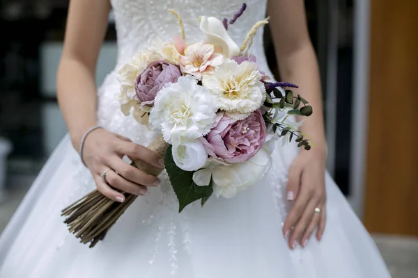 Невеста в белом платье и букет цветов в ее руке — стоковое фото
