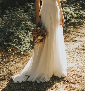 Beyaz elbiseli gelin ve elinde bir demet çiçek.