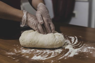 Türkiye 'de masada plastik eldivenle hamur yapan bir kadının elleri