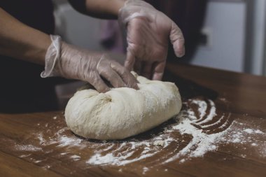 Türkiye 'de masada plastik eldivenle hamur yapan bir kadının elleri