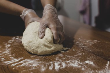 Türkiye 'de masada plastik eldivenle hamur yapan bir kadının elleri