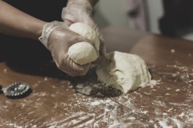 Türkiye 'de masada plastik eldivenle hamur yapan bir kadının elleri