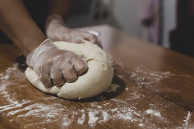 Türkiye 'de masada plastik eldivenle hamur yapan bir kadının elleri