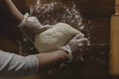 Türkiye 'de masada plastik eldivenle hamur yapan bir kadının elleri