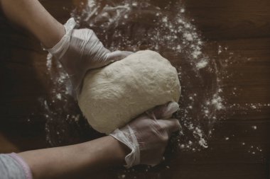 Türkiye 'de masada plastik eldivenle hamur yapan bir kadının elleri