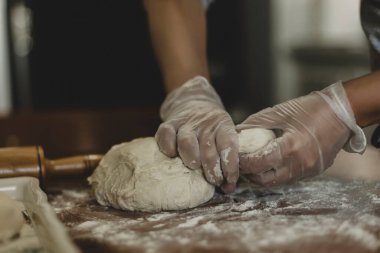 Türkiye 'de masada plastik eldivenle hamur yapan bir kadının elleri