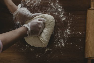 Türkiye 'de masada plastik eldivenle hamur yapan bir kadının elleri