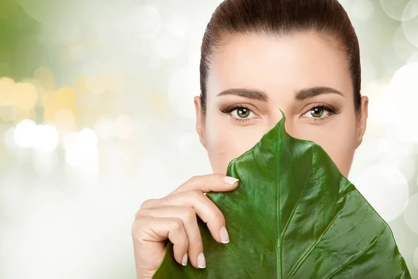 Hermosa joven con una hoja fresca en la cara — Foto de Stock