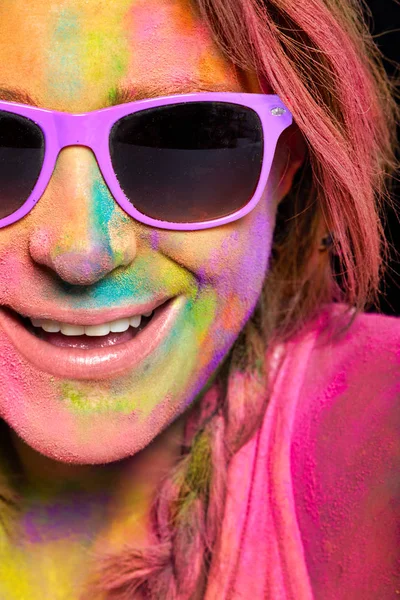 Beautiful young woman covered in rainbow colored Holi powder