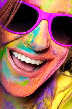 Holi 'yi kutlayan renkli tozla kaplanmış, gülen genç kadın.
