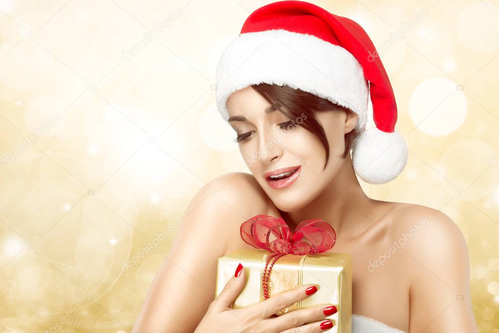 Beautiful Christmas girl clasping a gift