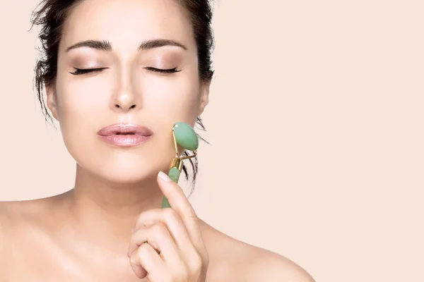 Vrouw met een gezonde frisse huid met behulp van jade face roller — Stockfoto