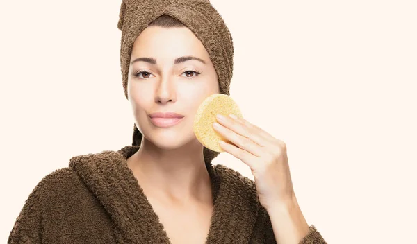 美容スポンジ付きの健康な肌の女性 美容ルーチンとスキンケアの概念 顔の化粧品の治療を適用する頭の中でバスローブとタオルを持つ美しい若い女性 スペースのコピー — ストック写真