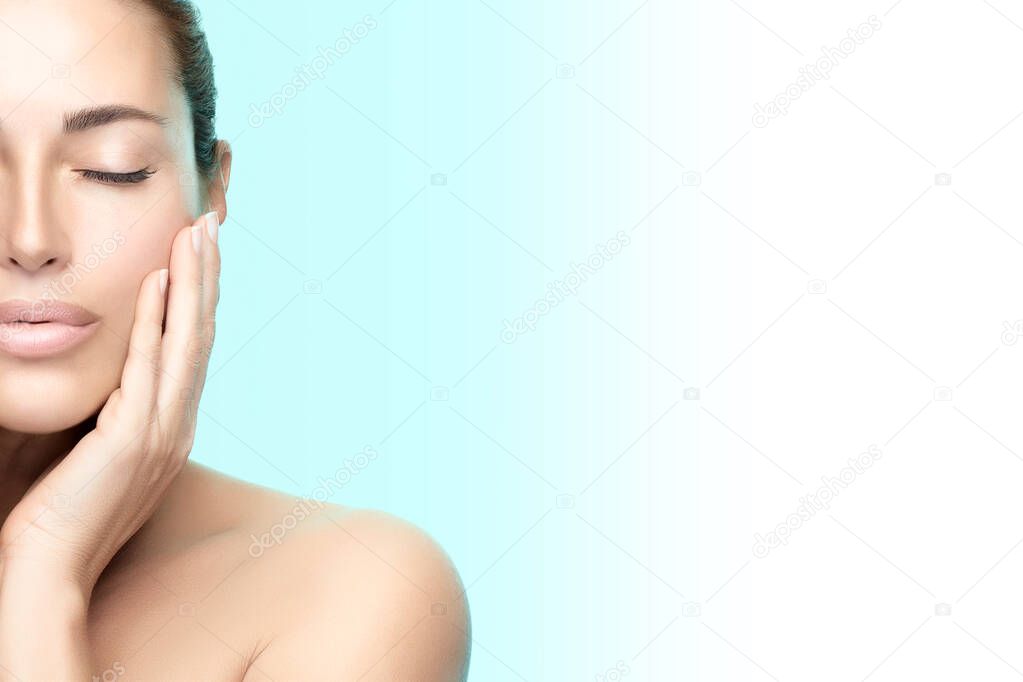 Beauty woman face. Beautiful brunette model girl with clean fresh skin, serene expression, hand to cheek, closed eyes. Half face over blue background. Cosmetology, Spa, Wellness and Skincare concept