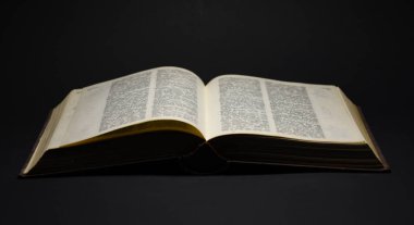 Siyah arkaplan üzerine açık sayfaları olan eski kitap
