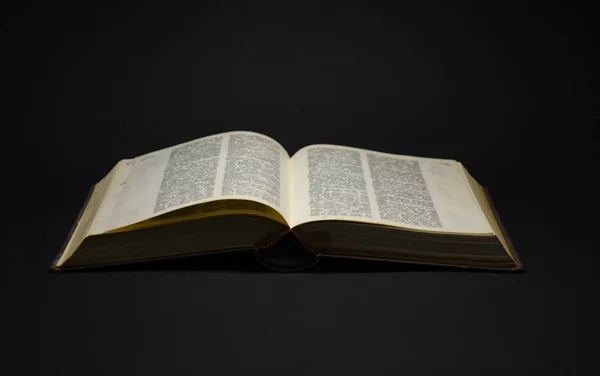 Siyah arkaplan üzerine açık sayfaları olan eski kitap