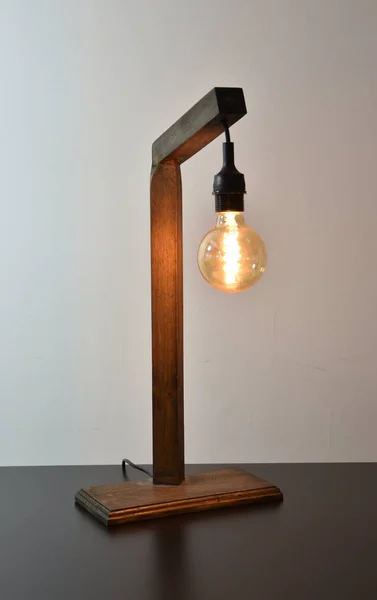 Handmade wooden lamp on gray background with retro edison bulb