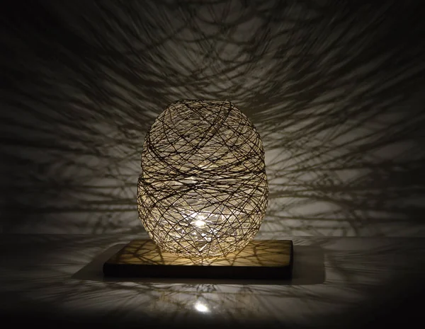 Duvarında gölgeler olan el yapımı ahşap ve halat lambası.