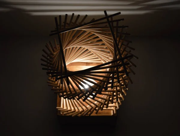 Handmade double hellix lamp from wood and bamboo sticks with shadows on the wall