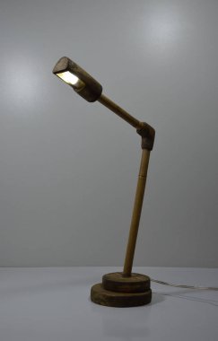 Gri arka planda el yapımı ahşap ve bambu masa lambası.