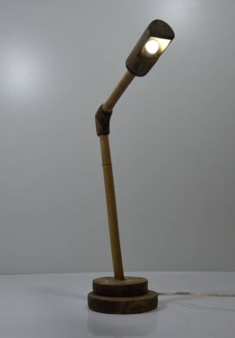 Gri arka planda el yapımı ahşap ve bambu masa lambası.