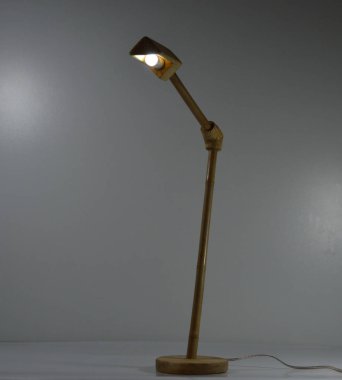 Gri arka planda el yapımı ahşap ve bambu masa lambası.