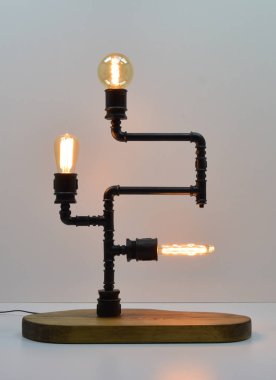 Gri arka planda el yapımı ahşap ve metal boru lambası